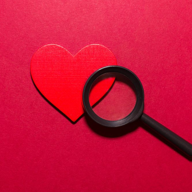 Red,heart,and,magnifier,on,red,background.,looking,for,love